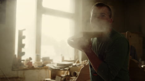 Handyman-blowing-on-wooden-plank-in-studio