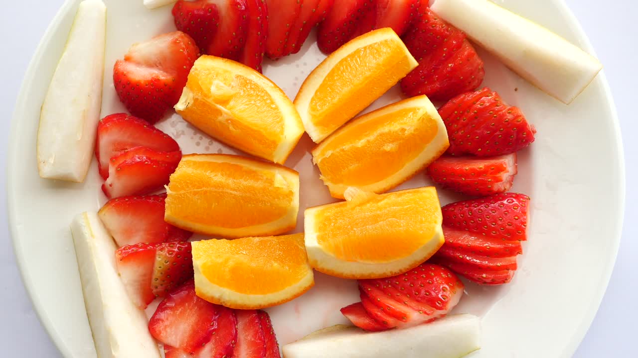 Ripe red strawberries and orange fruit on a plate
