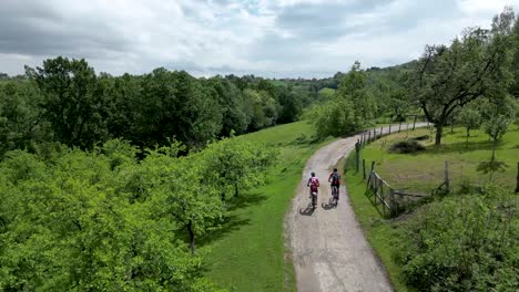 two mountain bikers ride bicycles with beautiful nature around them. drone shot in slow motion