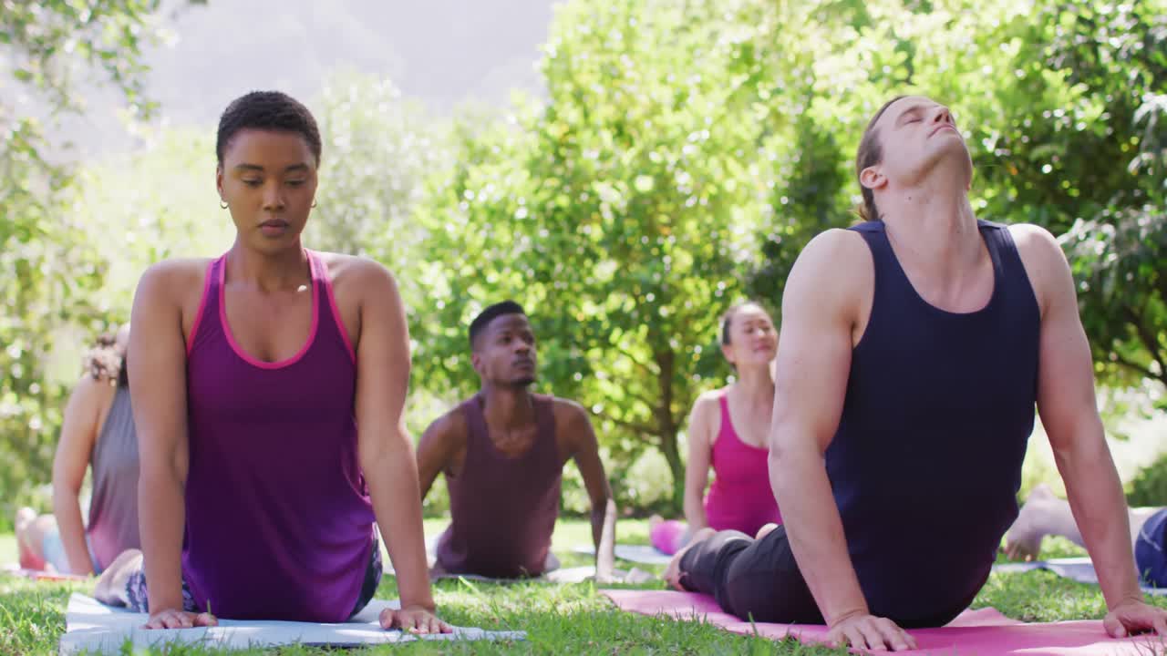grupo de jóvenes diversos meditando y practicando yoga juntos en el parque