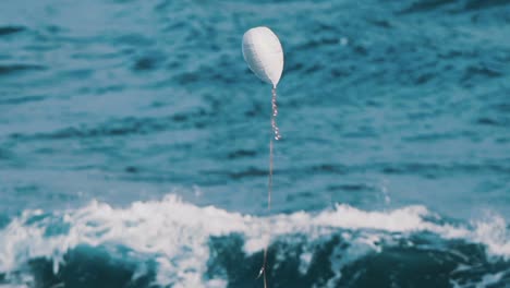 globo de helio blanco en forma de corazón ascendiendo frente al mar