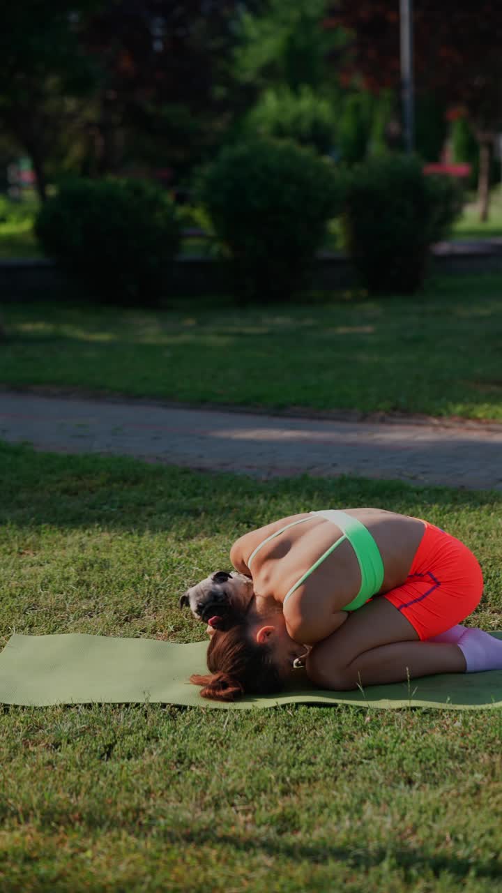 mujer haciendo yoga con un pug en el parque