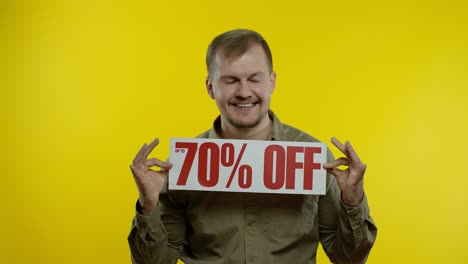 attractive man showing up to 70 percent off inscriptions signs, rejoicing good discounts, low prices