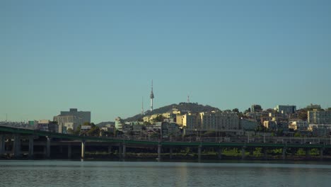 torre namsan de seúl y villas yongsang desde la orilla del río hangang, tráfico desde el puente hannam hasta la carretera de la autopista gangbyeon en el cielo azul sin nubes al atardecer