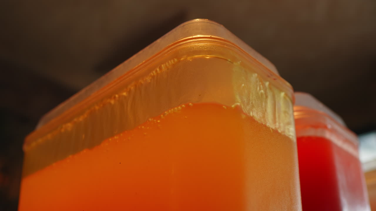 Amber juice in plastic dispenser corner on dark background