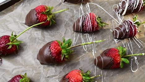 drizzling tray of strawberries dipped in chocolate with white chocolate