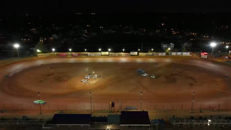 aerial flyaway shot of dirt track car racing at night