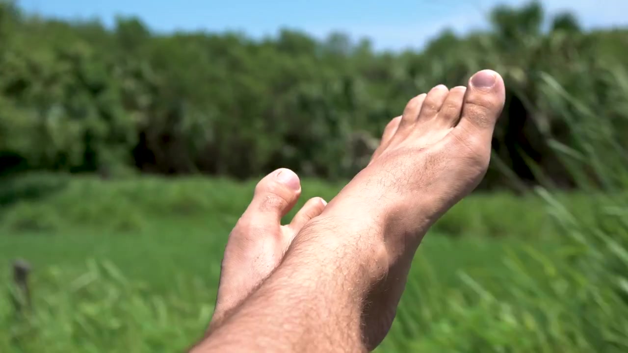 Piedi maschili che sporgono dal finestrino laterale dell'auto sulla costa occidentale della Bassa California, Messico. Primo piano attraverso il finestrino