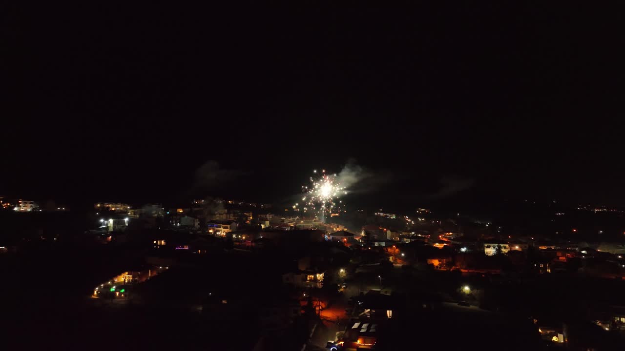Festive aerial view of a city at night with fireworks celebrating New Year's Eve
