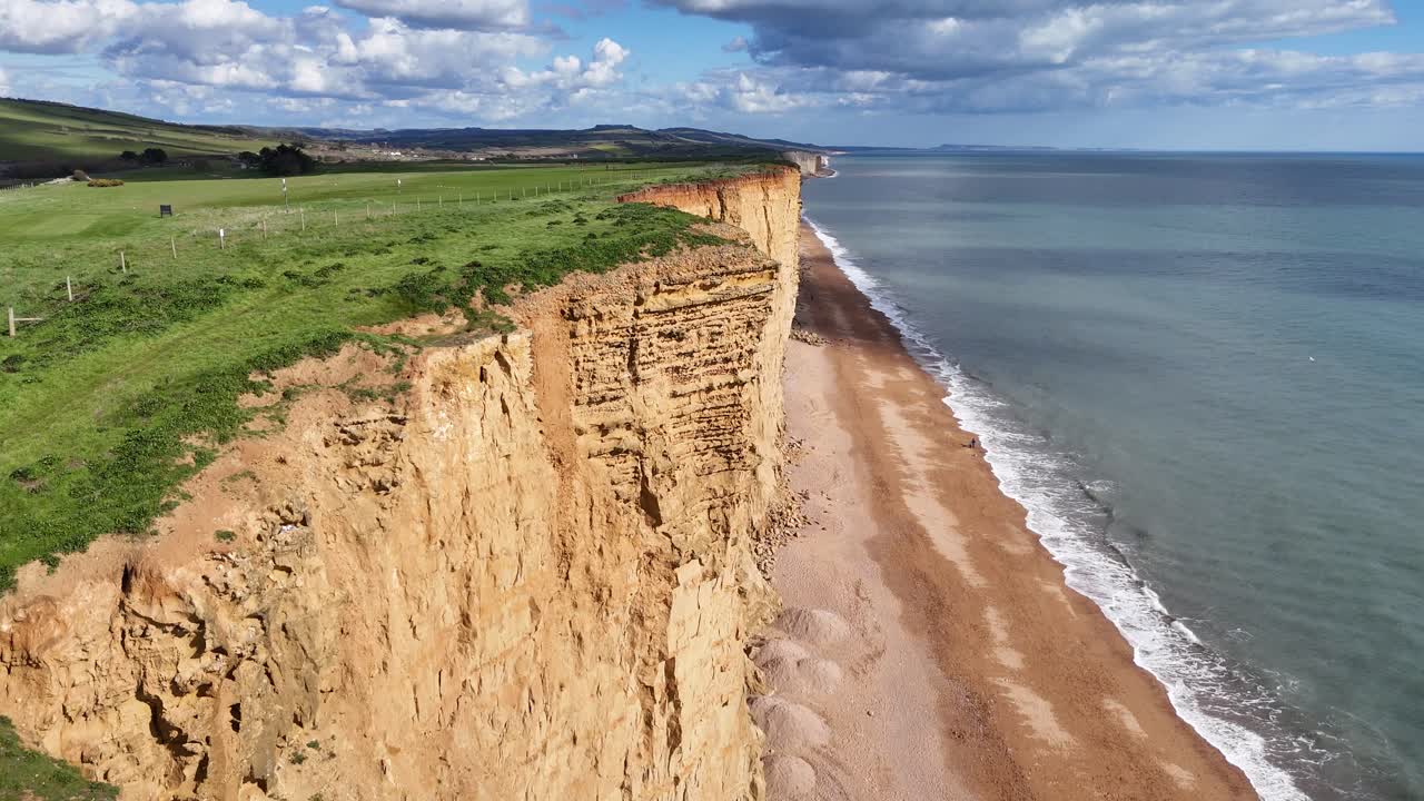 Ripresa aerea con drone in allontanamento che rivela le scogliere di arenaria di West Bay, Dorset, Regno Unito.