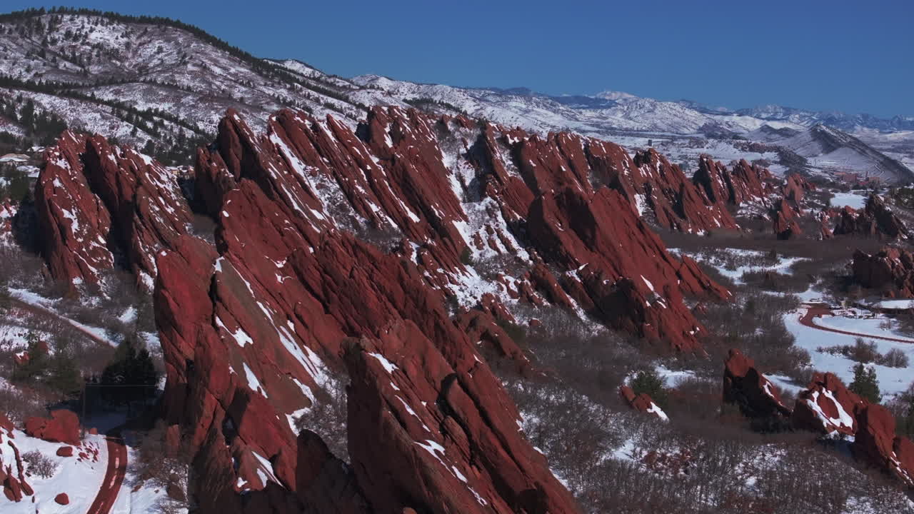 March winter morning snow stunning Roxborough State Park Littleton Colorado aerial drone over sharp jagged dramatic red rock formations Denver foothills front range landscape blue sky forward slowly