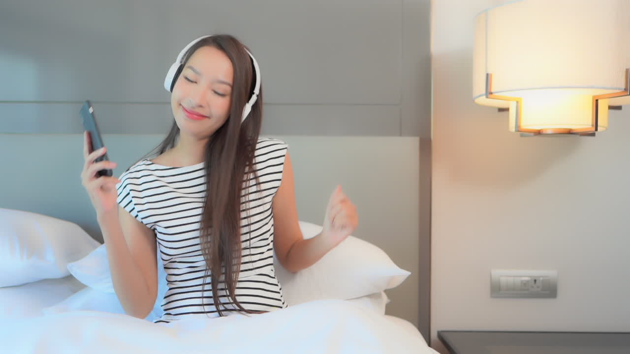 휴대전화의 앱을 사용하여 무선 헤드폰으로 블루투스를 통해 음악을 듣는 젊은 여성