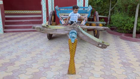 isolated-toddler-sitting-at-vintage-wood-bullock-cart-at-outdoor-at-evening