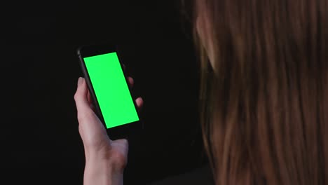 la mujer sostiene el teléfono con una pantalla verde.