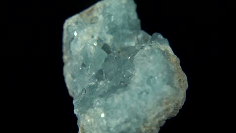 la rotación sin problemas de un mineral azul claro (celestina) frente a un fondo negro