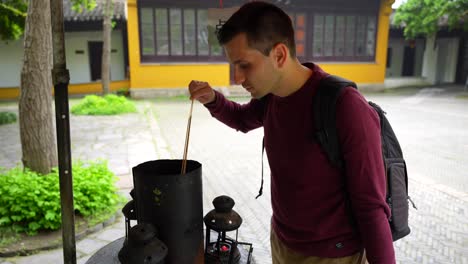 man lighting incense at a temple