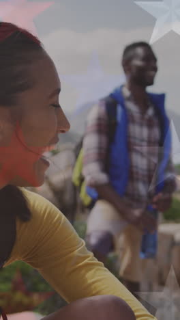 animation of american flag over smiling diverse couple sitting in mountains