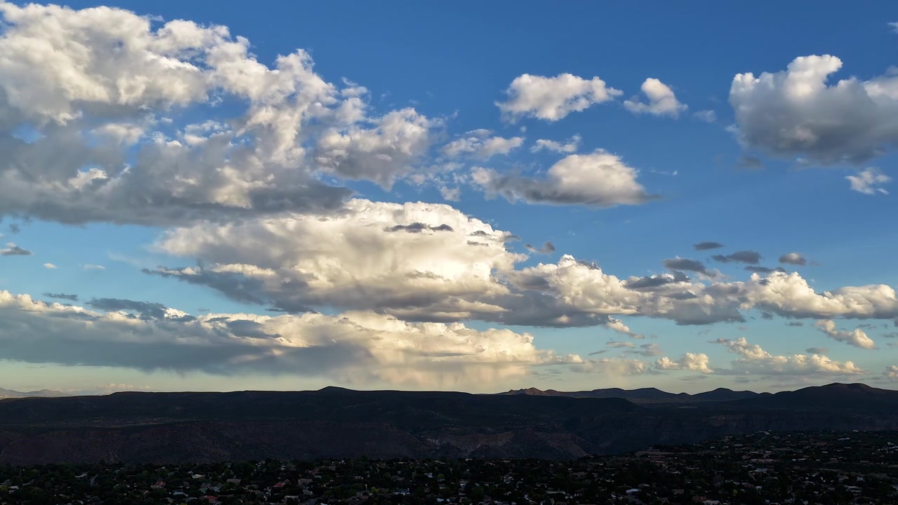 4K UHD drone-timelapse av dramatiske skyer som beveger seg over en vidstrakt sørvestlig canyonby ved solnedgang. Gyldent sollys skifter over den dype kløften og de ulendte åsene før det forsvinner inn i kveldsskyggen.