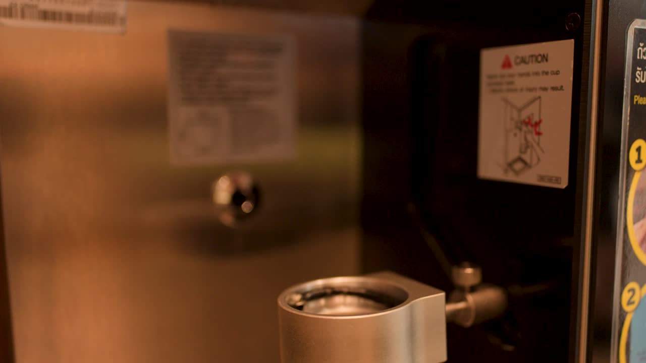 Close-up shot of an automated machine dispensing vanilla soft serve into a paper cup