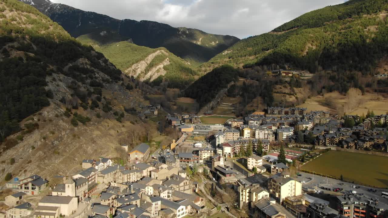 Aerial perspective of Andorran town in mountain valley with forest and fields. European alpine community, scenic travel and nature overview