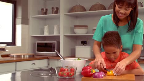 una madre hispana sonriente está cocinando con su hijo