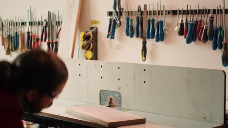 man putting on protection gear while inserting plank in spindle moulder