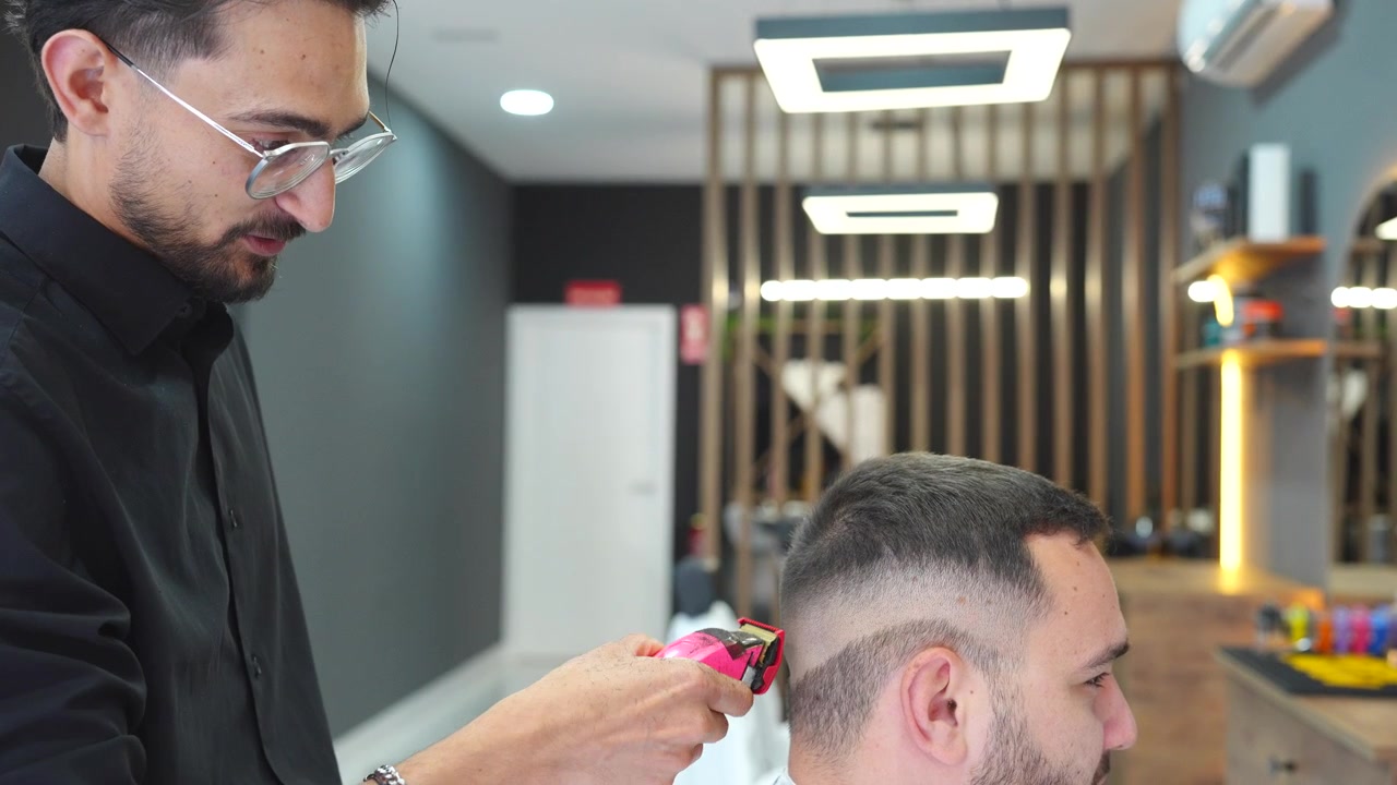Professionel barber der omhyggeligt trimmer en kundes hår med en moderne elektrisk trimmer