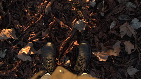 kicking up autumn leaves in slow motion with black boots