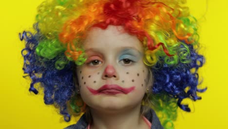 Little-child-girl-clown-in-colorful-wig-tells-something-interesting.-Having-fun,-smiling.-Halloween