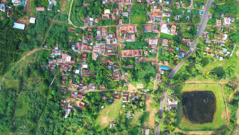 sprawling countryside village brightly lit by sunlight showing green lush farmlands, aerial zenithal view