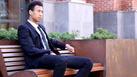 pensive serious african businessman sitting on bench