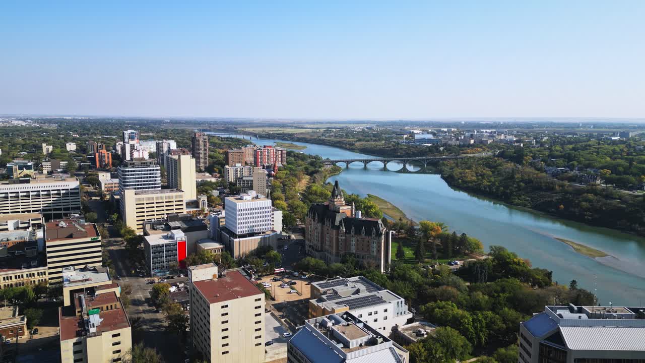 Drone shot shows Saskatoon bridge spanning river into downtown core, fall day