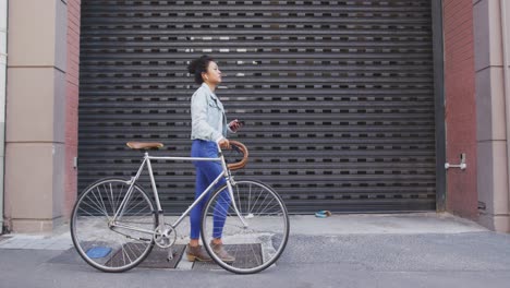 mixed race woman walking next to her bike on the street