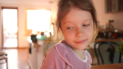 cute kid girl portrait holds stick insect pet in hands and put it on her face at home have fun and smile