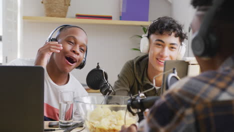 happy diverse male teenage friends using laptop and recording podcast, slow motion