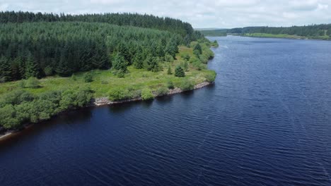 idyllic blue water reservoir lake woodland hiking walk aerial view slow reverse descend