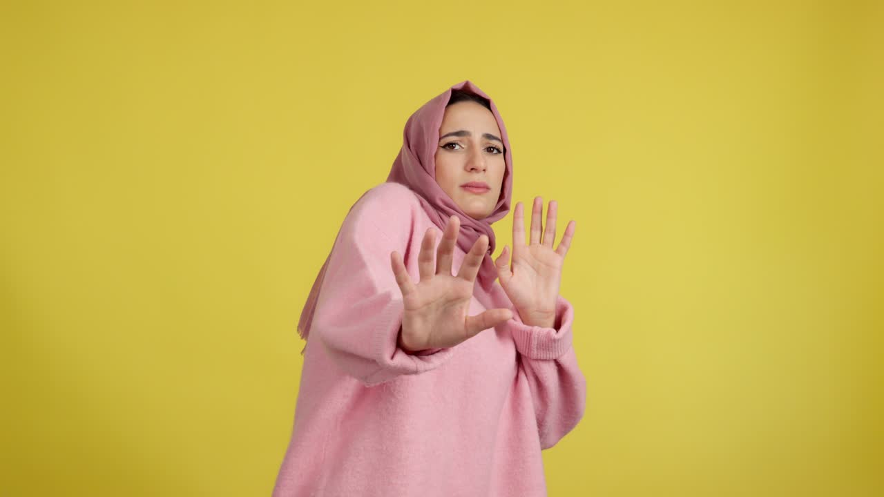Woman in pink hijab making a stop or rejection gesture