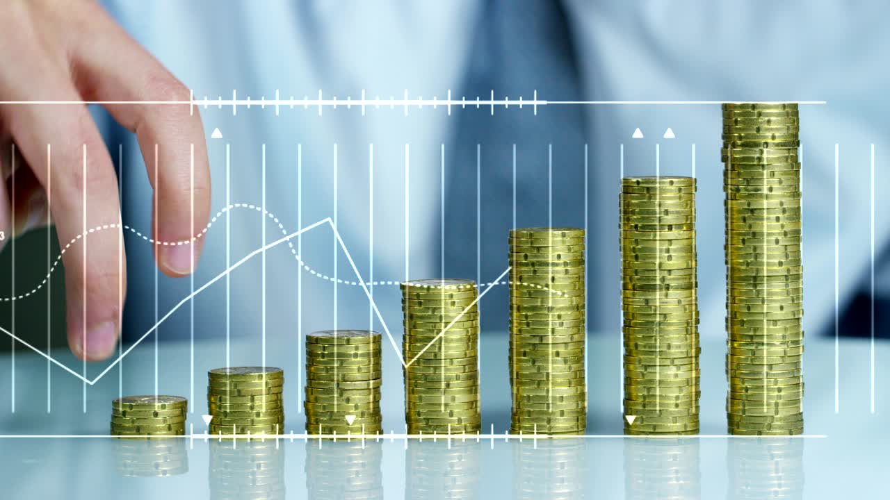 un hombre de negocios con traje y corbata tiene ante sí muchas pilas de monedas de oro. el hombre de negocios cuenta y vigila el dinero cuidadosamente.