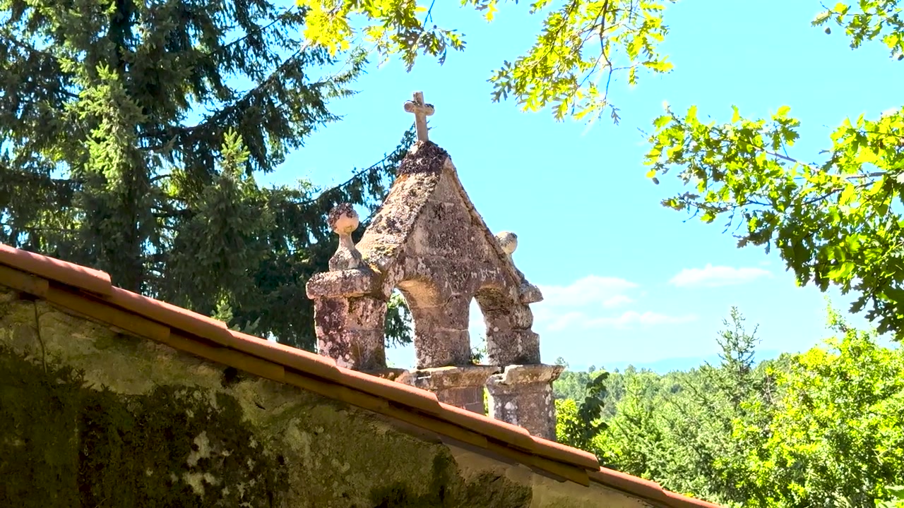 Campanile a vela in pietra incorniciato da alberi a San Pedro de Rocas a Esgos, Ourense, Galizia, Spagna