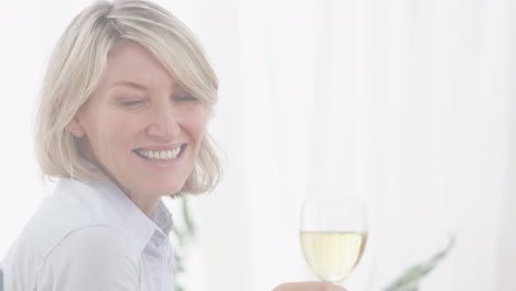 video de una mujer caucásica sonriente bebiendo vino blanco.