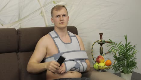 man with broken arm sitting on couch