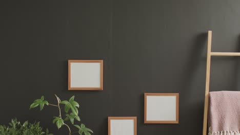 marco de madera con espacio de copia en fondo blanco con plantas contra la pared gris.