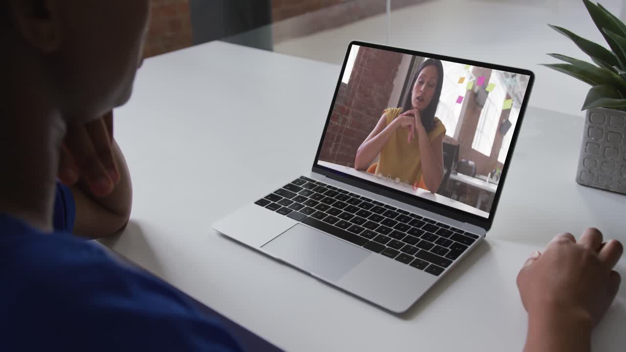 African american businesswoman sitting at desk using laptop having video call with female colleague