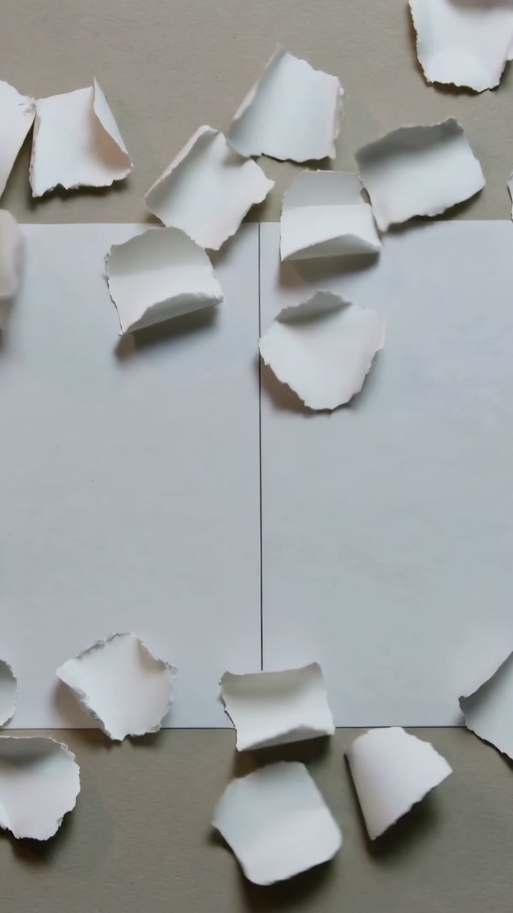Vertical video: Two white sheets receiving torn fragments from top, covering seam for paper design