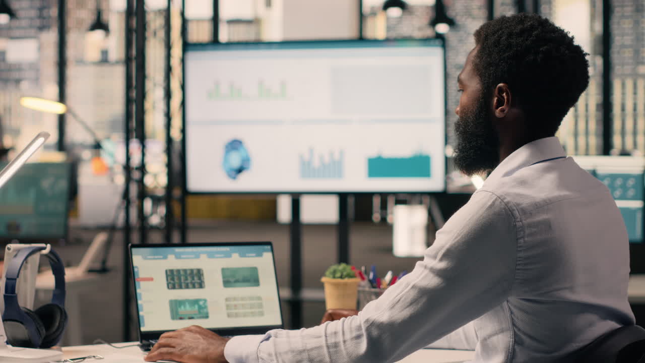 African american businessman, data analysis on laptop, performance review,