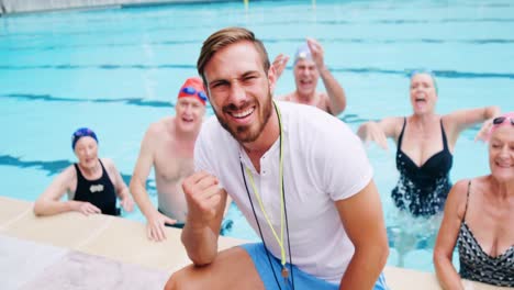 portrait of swim trainer and seniors at poolside