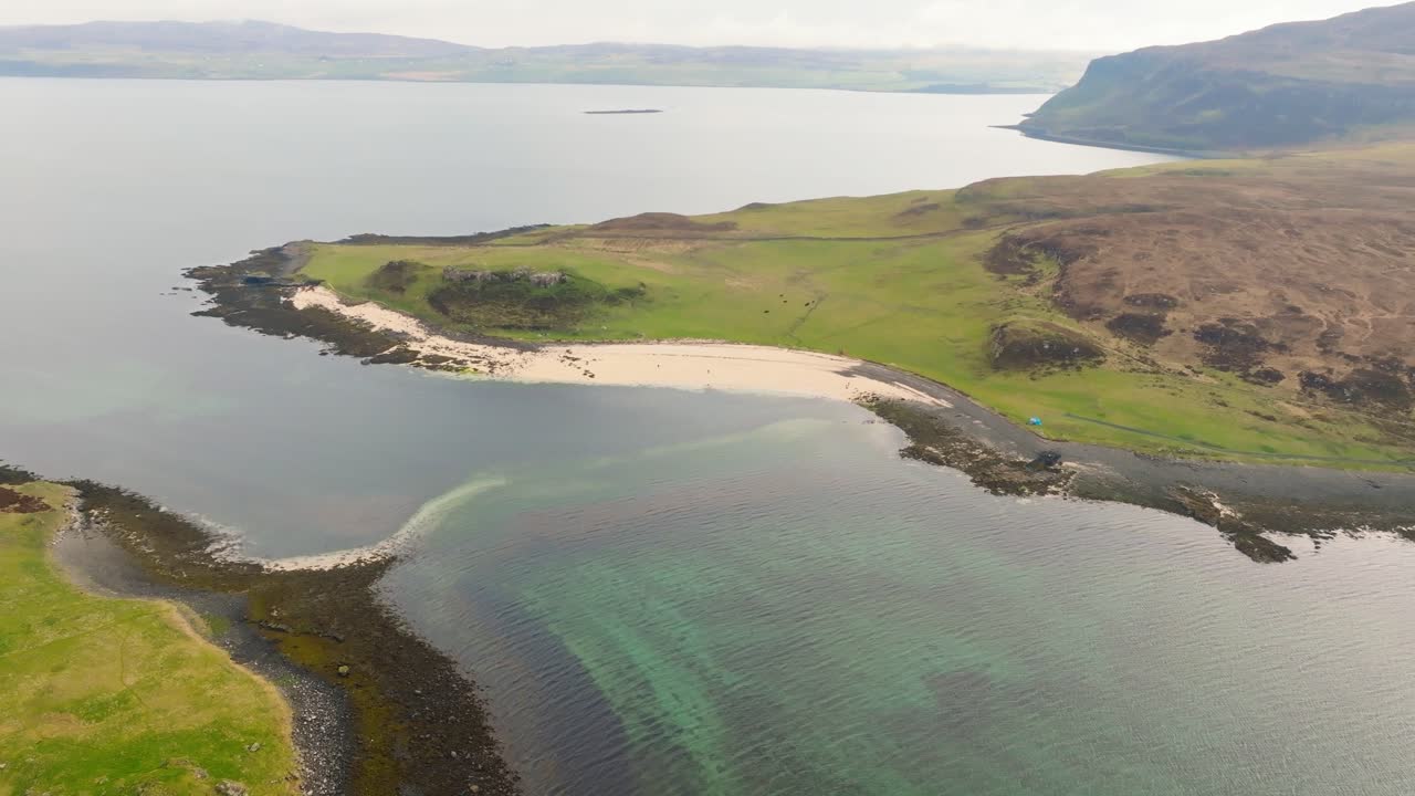 Aerial drone shot of Coral Beach on the Isle of Skye, Scotland, with turquoise waters, white sand, and surrounding green hills creating a stunning coastal landscape