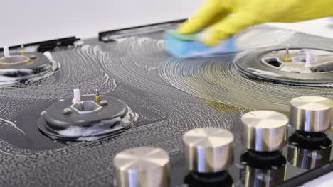 cleaning a dirty gas hob with foam and a sponge