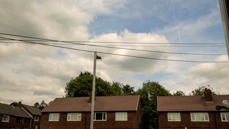 very animated clouds with an english red brick housing and powerlines in shot