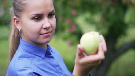 a young girl in a blue shirt looks at an apple in her hand